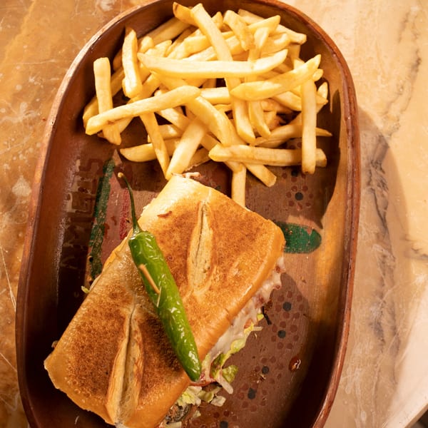 Amigos Mexican Cuisine's torta sandwich with a green chili and a side of golden french fries.